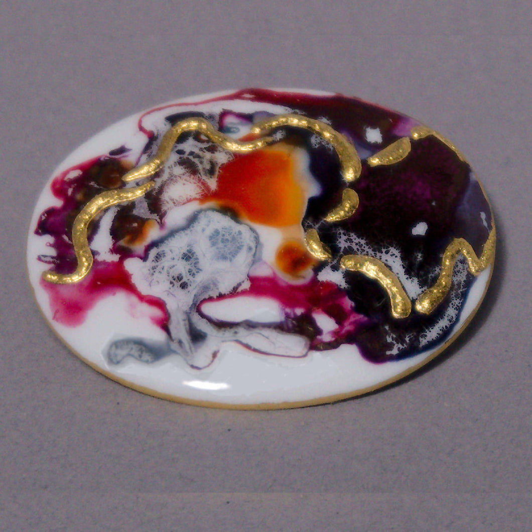 Oval brooch in black, carmine and amber